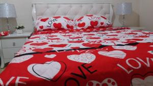 a bed with a red and white bedspread with hearts at Dorit Vacation in Tiberias