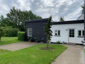 a black and white house with a tree in the yard at Tusindfrugt B&B in Store Heddinge