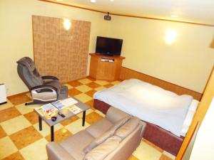 a room with a bed and a couch and a tv at Annex Tamayu 大人専用 in Matsue