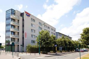 - un bâtiment blanc dans une rue de la ville arborée dans l'établissement Residhome Val d'Europe, à Montévrain