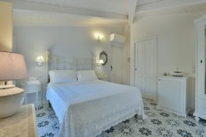 a white bedroom with a white bed and a lamp at A casa di Nonna Bianca in Santa Maria di Castellabate