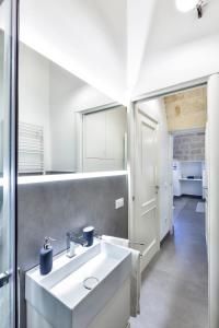 ein Badezimmer mit einem weißen Waschbecken und einem Spiegel in der Unterkunft A la muràgghje "A" in Monopoli
