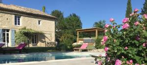 una casa con piscina en un patio con rosas rosas en Chambres d'Hôtes Le Val de la Garenne en Senouillac