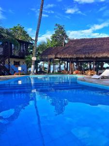 a pool at a resort with a thatched building at Pousada Capitão Thomaz in Jericoacoara