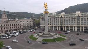un grande edificio con una statua in mezzo a una strada di The Passenger Rooms a Tbilisi City