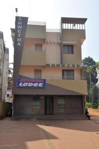 a building with a sign on the side of it at Shwetha Lodge in Kollūru