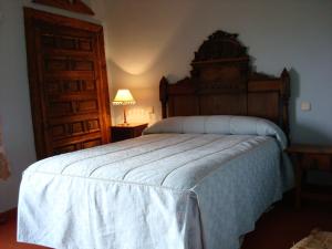 a bedroom with a large bed with a wooden headboard at Posada de San Millán in Sepúlveda