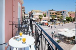 a balcony with two drinks on tables on a city street at Vener Luxury Suites in Chania