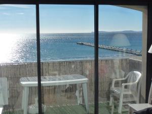 een balkon met een tafel en stoelen en uitzicht op de oceaan bij Les pieds dans l’eau in La Croix-Valmer