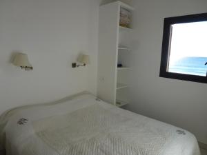 een witte slaapkamer met een bed en een raam bij Les pieds dans l’eau in La Croix-Valmer