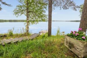 a lake with a wooden dock and flowers in a wooden box at Hiekkarannanlomat in Kannonkoski