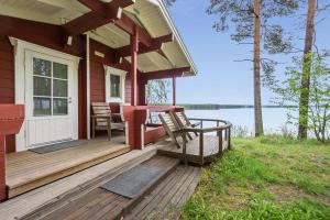 a wooden porch of a house with a table and chairs at Hiekkarannanlomat in Kannonkoski