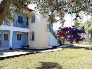 a white house with flowers hanging from a tree at Don Bazilio Seahouse in Leptokarya