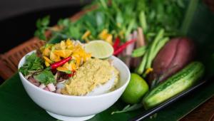 a bowl of food sitting on a table with vegetables at Borei Angkor Resort & Spa in Siem Reap