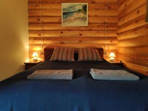 Un dormitorio con una cama en una cabaña de troncos en Brīvdienu mājiņas Zemzari, en Jūrkalne