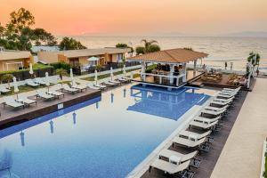 a beach area with a pool, chairs, and tables at Villa Di Mare Seaside Suites in Ixia