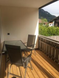 a glass table and two chairs on a wooden deck at Ferienwohnungen Alpenflair - barrierefrei urlauben in Oberammergau