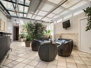 eine Außenterrasse mit Korbstühlen und einem TV in der Unterkunft Residence Chryseis in Cannes