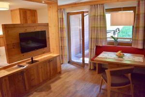 ein Wohnzimmer mit einem TV und einem Esstisch in der Unterkunft Appartements Kolberhof in Alpbach