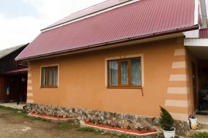 una casa con tetto rosso e muro di pietra di Карпатське сяйво a Vizhni Siniyvir