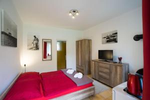 a bedroom with a red bed and a flat screen tv at Zánka Vízparti Üdülő in Zánka