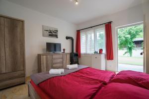 a bedroom with a large bed with red sheets and a window at Zánka Vízparti Üdülő in Zánka +34 photos