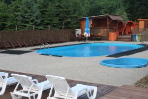 a swimming pool with white chairs and a table at Natura Park in Baligród