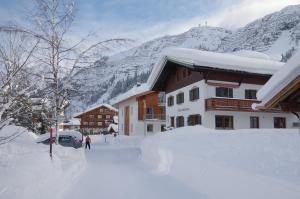 a building covered in snow next to a mountain at Hubertusklause in Lech am Arlberg