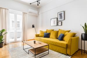 een gele bank in een woonkamer met een tafel bij Central Cozy Apartments in Plaka by UPSTREET in Athene