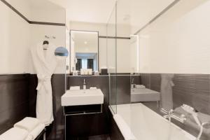 a bathroom with a sink and a mirror and a tub at XO Hotel Paris in Paris +66 photos