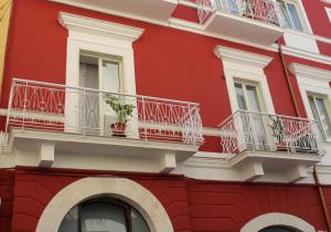 czerwony budynek z białym balkonem i rośliną w obiekcie Mulberry House w mieście Trani