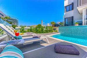 - un balcon avec une piscine et des chaises longues à côté d'un bâtiment dans l'établissement Bel Residence, à Split