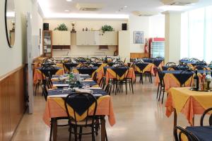 una stanza piena di tavoli e sedie con tovaglia gialla e blu di Hotel Loretta a Rimini