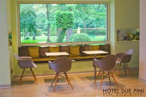 a room with a bench with chairs and a large window at Hotel Due Pini in Formigine