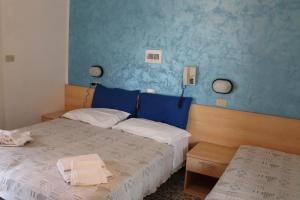 una camera con due letti e una parete blu di Hotel Loretta a Rimini