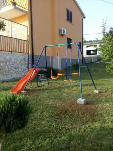 a playground with an orange and blue slide in a yard at Apartman Knapić in Koromačno