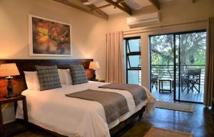 1 dormitorio con 1 cama grande y balcón en Bushveld Terrace - Hotel on Kruger en Phalaborwa