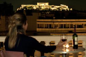 a woman sitting at a table with a glass of wine at Athens Odeon Hotel in Athens