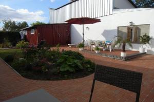 a patio with an umbrella and tables and chairs at ostseenahe Gartenidylle EG in Ribnitz-Damgarten