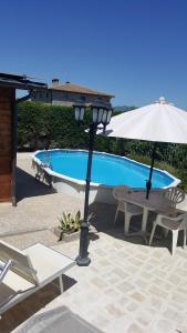 une terrasse avec une table, un parasol et une piscine dans l'établissement Villetta in Collina Toscana, à Marciano Della Chiana