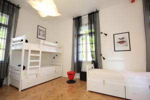 a bedroom with white bunk beds and a red chair at The Hostel in Zadar