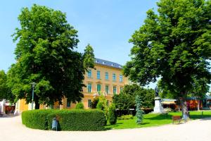 a large yellow building with trees in front of it at Ipoly Hotel Boutique Rooms & Suites in Balatonfüred