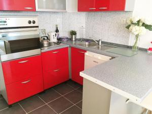 uma cozinha com armários vermelhos e um forno de fogão branco em Apartman Marina em Mostar