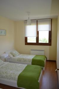 a bedroom with three beds with green sheets and a window at Los Nietos in Briones