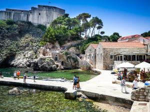 un grupo de personas de pie cerca del agua frente a un castillo en Munroe Apartment, en Dubrovnik