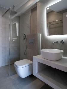 a bathroom with a sink and a toilet and a mirror at Olympos Suites Apartments in Leptokaria