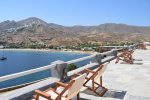 a row of chairs sitting on a ledge next to the water at Studios Niovi Serifos in Livadi