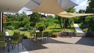 un patio con mesas y sillas bajo una sombrilla en Guesthouse Pri Mihelovih en Sežana