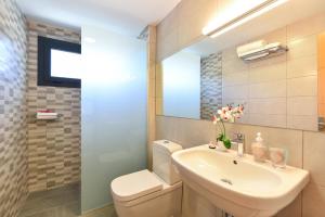 a bathroom with a sink and a toilet and a mirror at BeachFront Suites Morea Puerto Rico by VillaGranCanaria in Puerto Rico de Gran Canaria