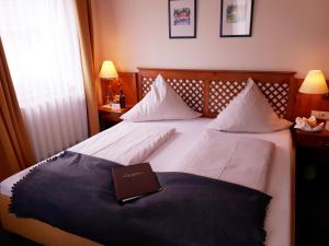 a hotel room with a bed with a book on it at Brauereigasthof Dachsenfranz in Zuzenhausen